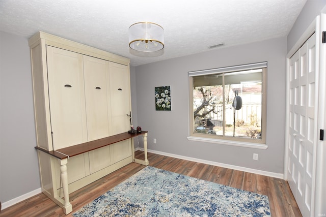 interior space featuring a textured ceiling, baseboards, and wood finished floors