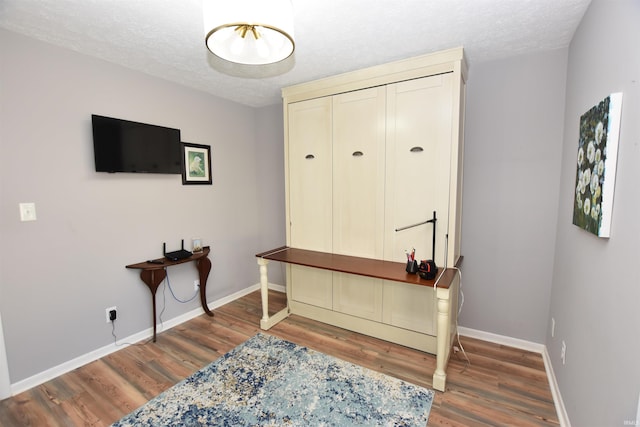 office space with a textured ceiling, baseboards, and wood finished floors