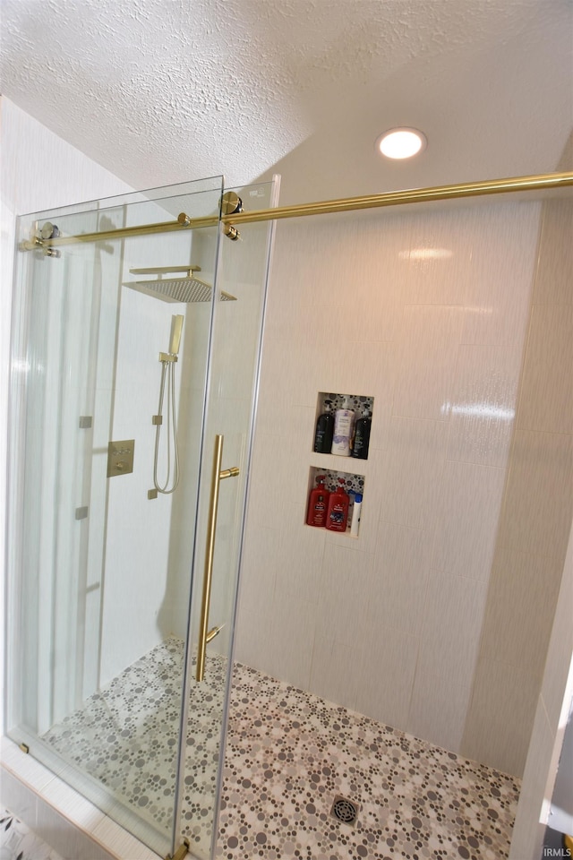 full bath with a stall shower, a textured ceiling, and recessed lighting