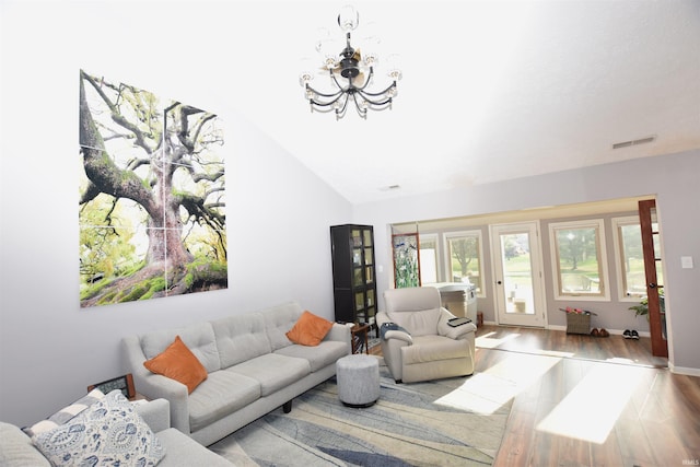 living room featuring a chandelier, lofted ceiling, wood finished floors, visible vents, and baseboards