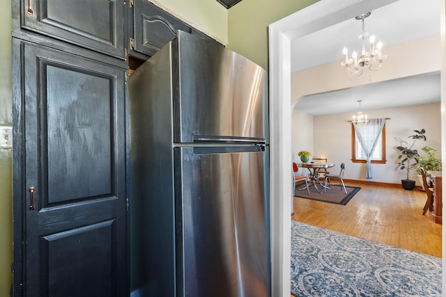 kitchen featuring freestanding refrigerator, hanging light fixtures, arched walkways, and an inviting chandelier