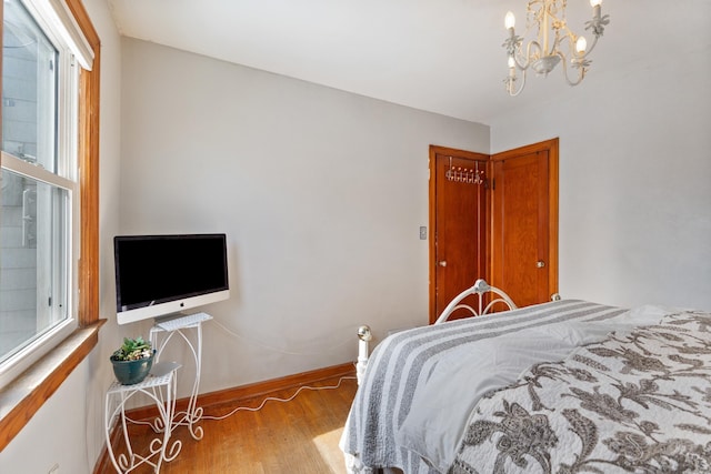 bedroom featuring baseboards, light wood-style flooring, and a notable chandelier