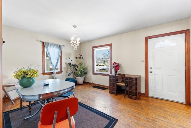 dining area with baseboards, light wood-style flooring, a chandelier, and a wealth of natural light