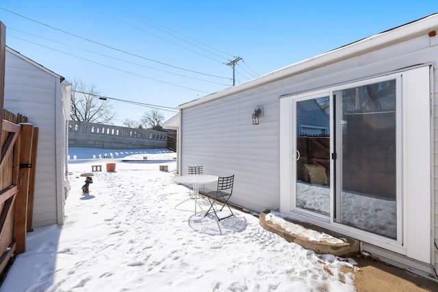 snow covered patio featuring fence