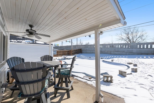 snow covered patio featuring a fenced backyard, ceiling fan, and outdoor dining space