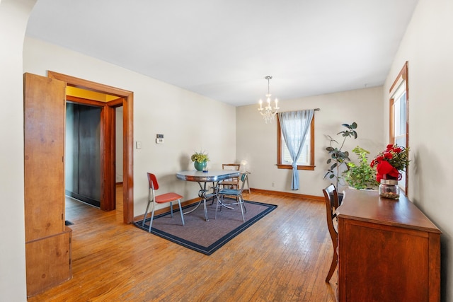 dining space with baseboards, light wood-style flooring, and an inviting chandelier