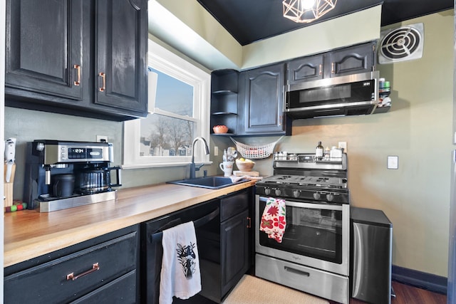 kitchen with stainless steel appliances, a sink, visible vents, baseboards, and open shelves