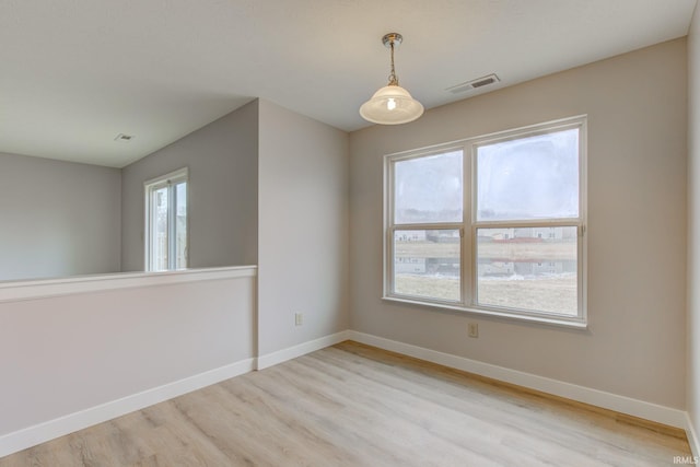 spare room with light wood-style floors, visible vents, and baseboards