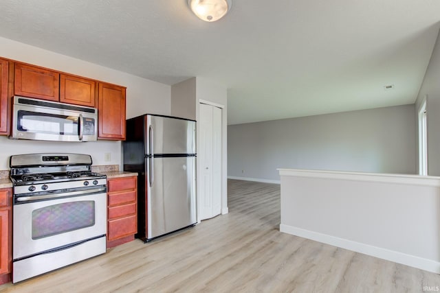 kitchen featuring stainless steel appliances, light wood-type flooring, light countertops, and baseboards