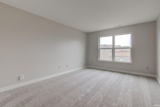 unfurnished room with visible vents, light colored carpet, and baseboards