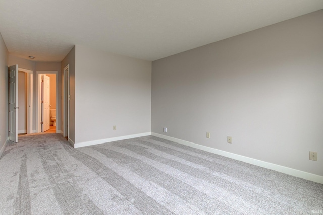 spare room featuring carpet and baseboards