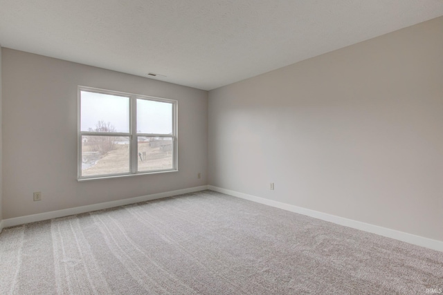 carpeted empty room featuring visible vents, a textured ceiling, and baseboards