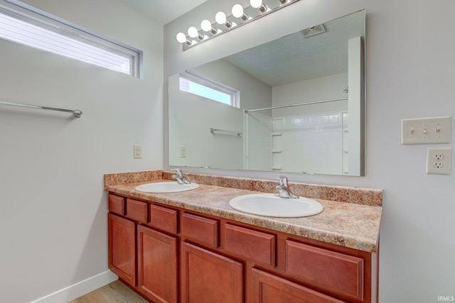 full bath featuring double vanity, visible vents, baseboards, and a sink