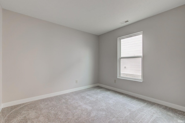 empty room featuring baseboards, visible vents, and light colored carpet