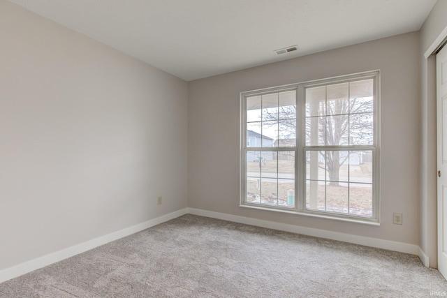 spare room with light colored carpet, a healthy amount of sunlight, and visible vents