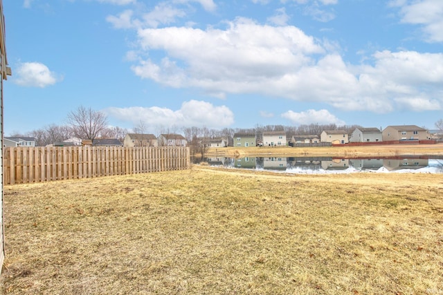 view of yard with a residential view, a water view, and fence