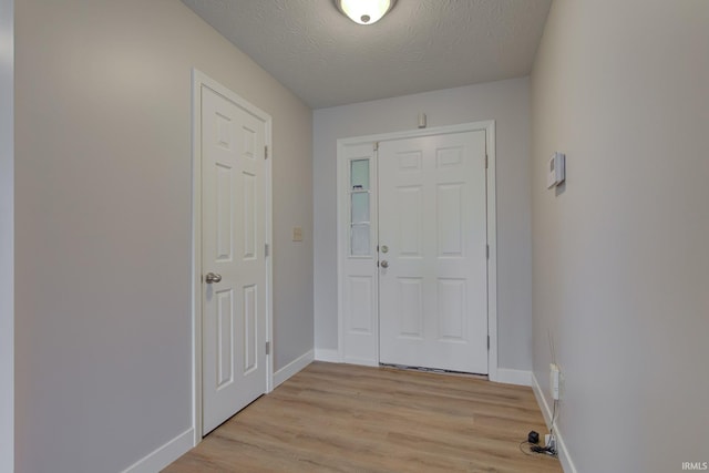 entrance foyer with light wood-style flooring, baseboards, and a textured ceiling