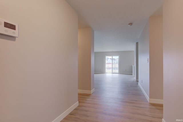 hall featuring light wood finished floors and baseboards