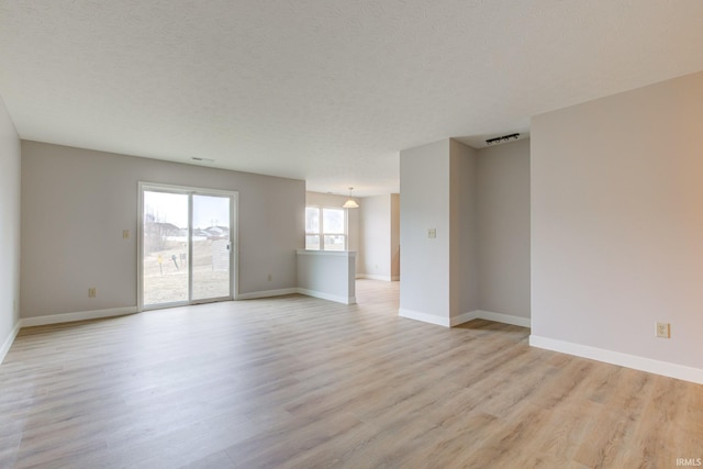 spare room with light wood-type flooring, visible vents, and baseboards