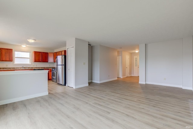 kitchen with open floor plan, light countertops, appliances with stainless steel finishes, and light wood-type flooring