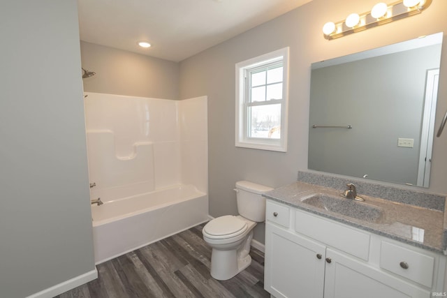 full bathroom with toilet, washtub / shower combination, vanity, wood finished floors, and baseboards