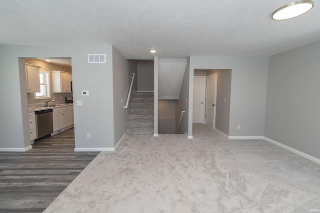 unfurnished living room featuring stairway, a sink, visible vents, and baseboards