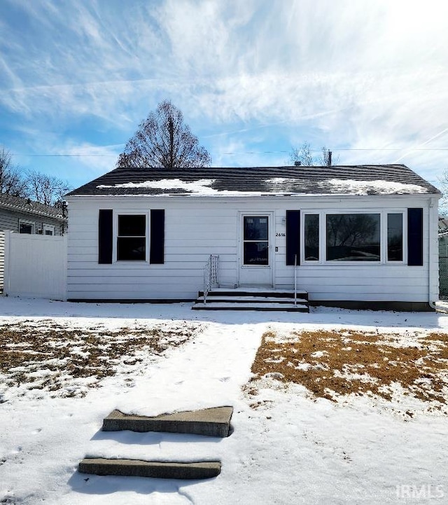 snow covered house featuring fence