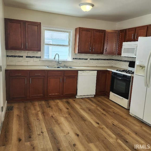 kitchen with white appliances, dark wood-type flooring, light countertops, and a sink