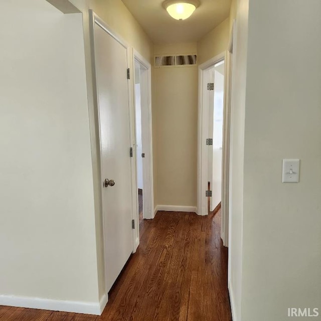 hallway with dark wood finished floors and baseboards