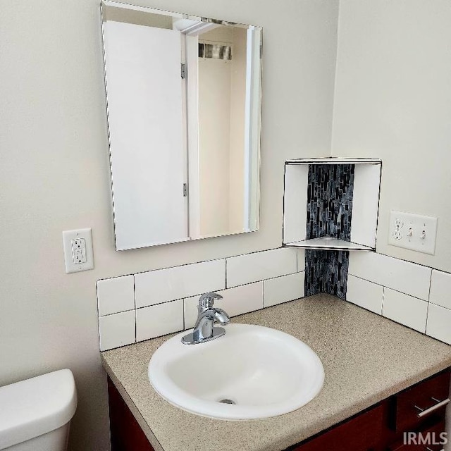 half bathroom featuring vanity, toilet, and decorative backsplash