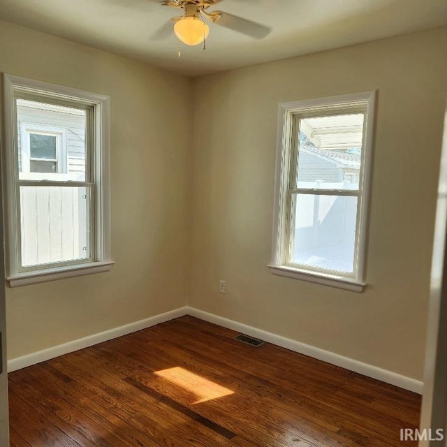 spare room with ceiling fan, dark wood finished floors, visible vents, and baseboards