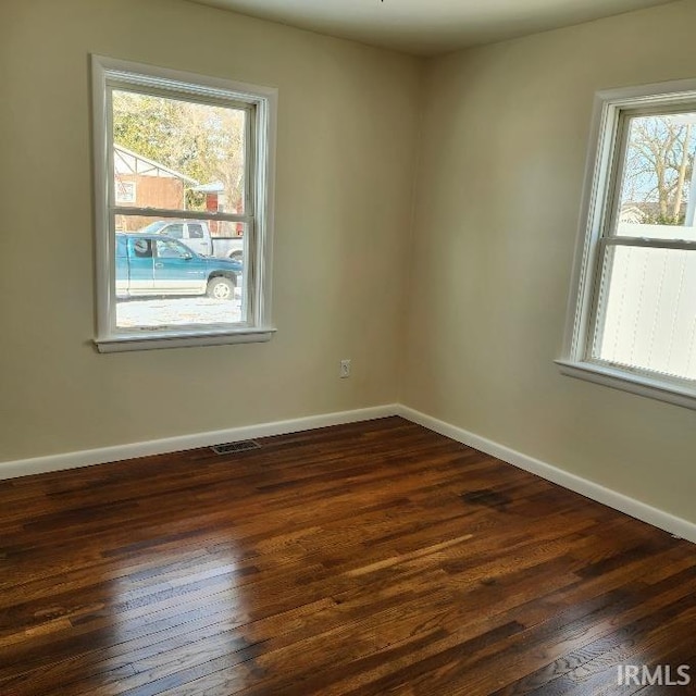 empty room featuring baseboards and dark wood finished floors