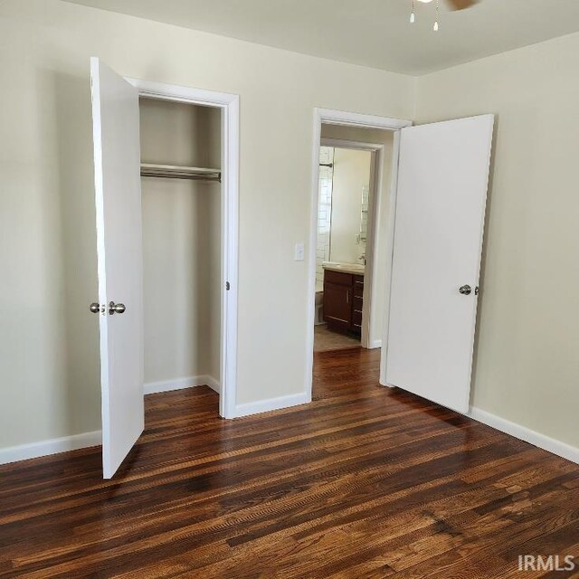 unfurnished bedroom with a closet, dark wood-style flooring, and baseboards