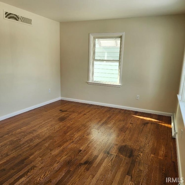 spare room with dark wood-style floors, baseboards, and visible vents