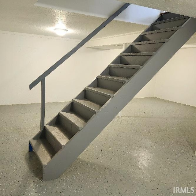 staircase with a textured ceiling and speckled floor