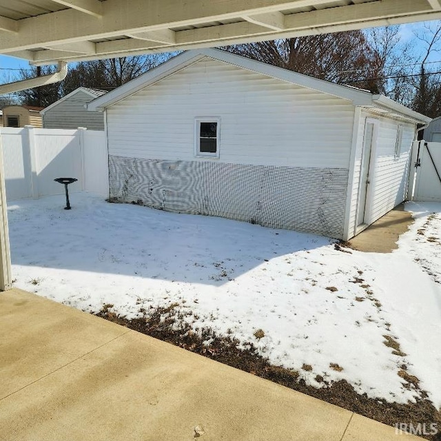 snow covered garage with fence