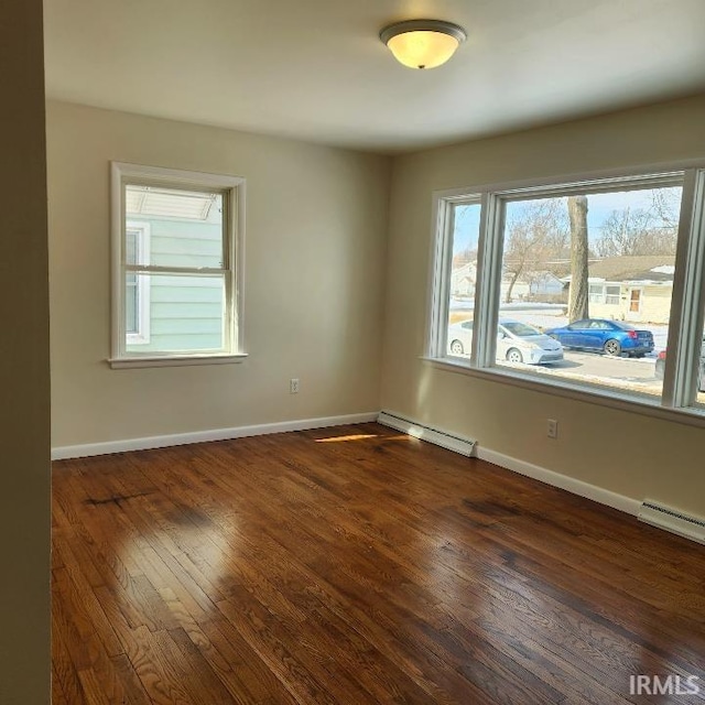 spare room featuring dark wood-style flooring, a baseboard radiator, and baseboards