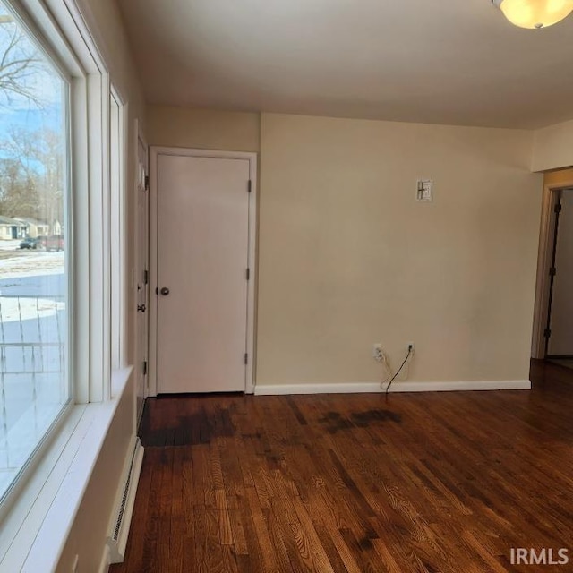 unfurnished room featuring dark wood-style floors, baseboards, and baseboard heating