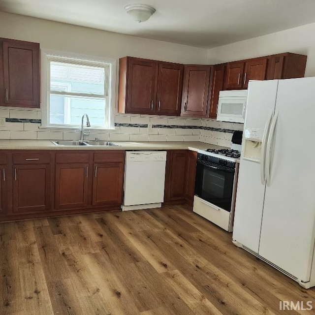 kitchen with white appliances, dark wood-type flooring, a sink, light countertops, and backsplash