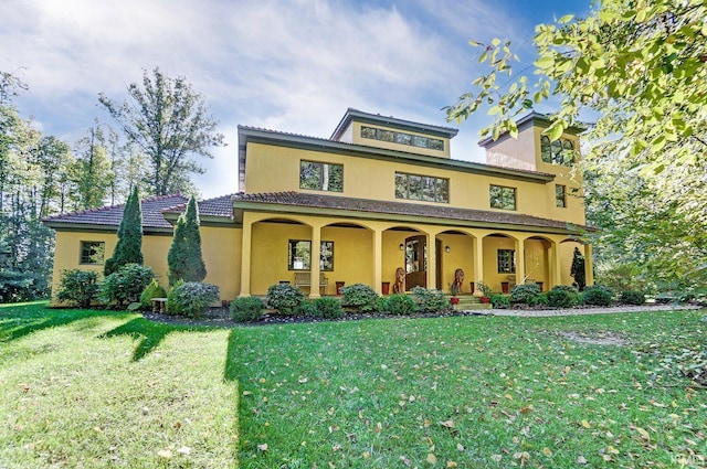 view of front facade featuring a front lawn, a porch, a tile roof, and stucco siding