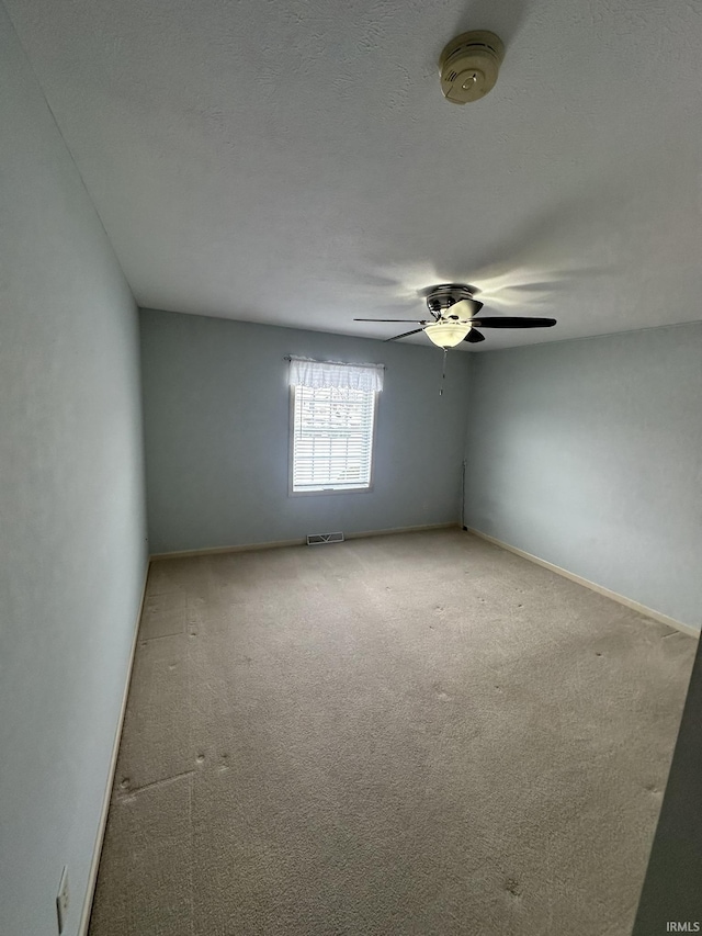 empty room with a textured ceiling, carpet flooring, visible vents, and baseboards