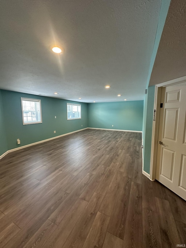 spare room with a textured ceiling, baseboards, and wood finished floors