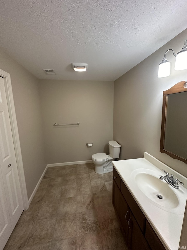 bathroom featuring visible vents, baseboards, toilet, a textured ceiling, and vanity