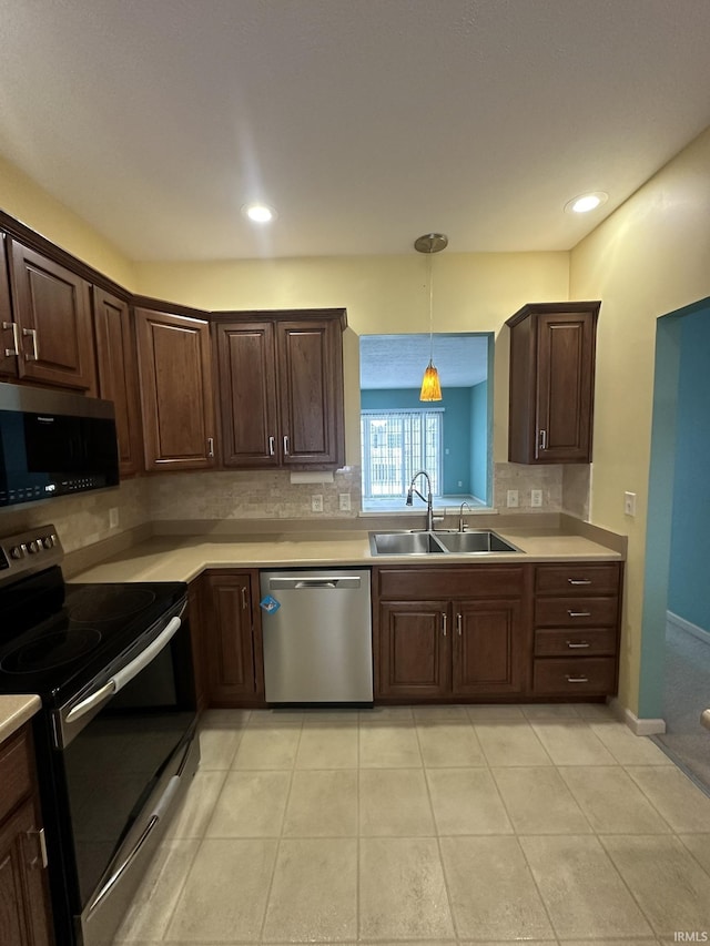 kitchen featuring decorative backsplash, decorative light fixtures, stainless steel appliances, light countertops, and a sink