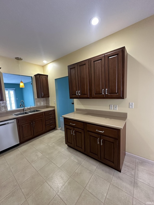 kitchen with a sink, light countertops, stainless steel dishwasher, backsplash, and decorative light fixtures