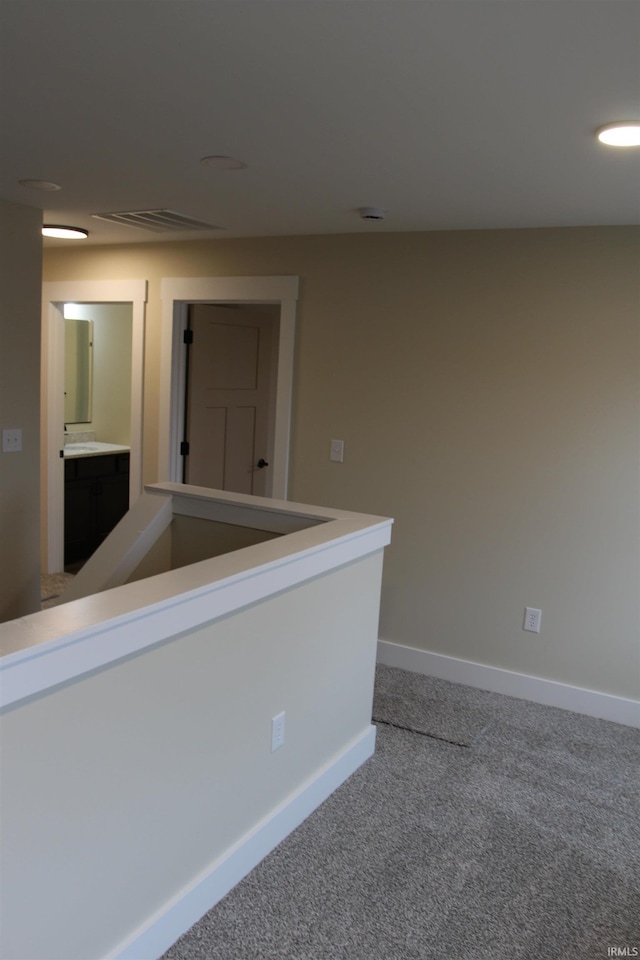 unfurnished room with carpet, visible vents, and baseboards