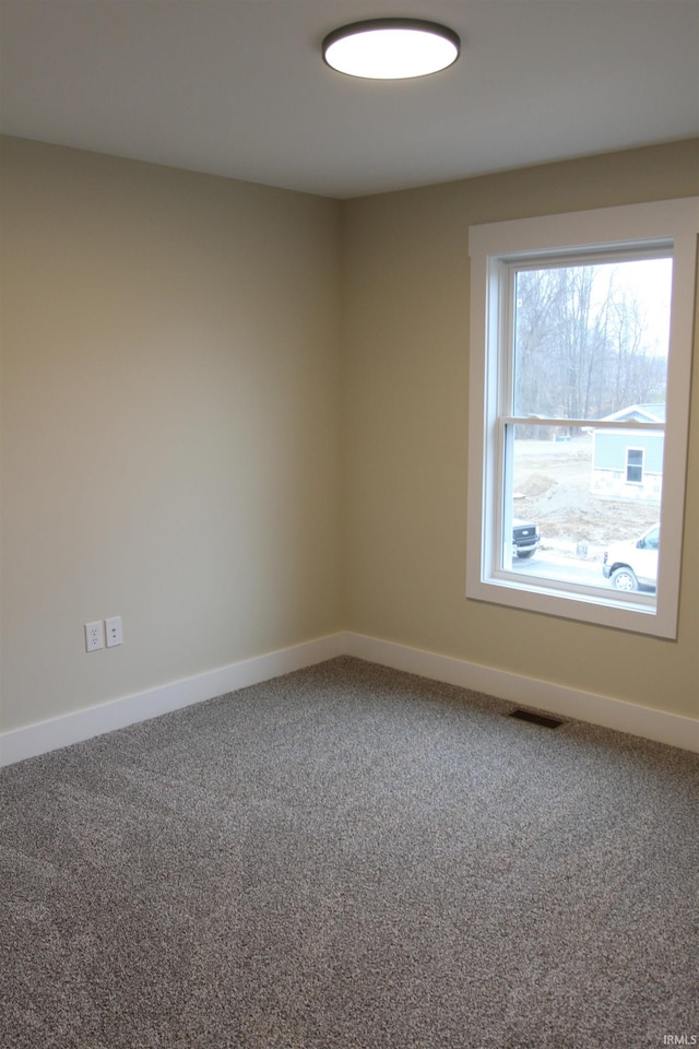 carpeted spare room featuring visible vents and baseboards