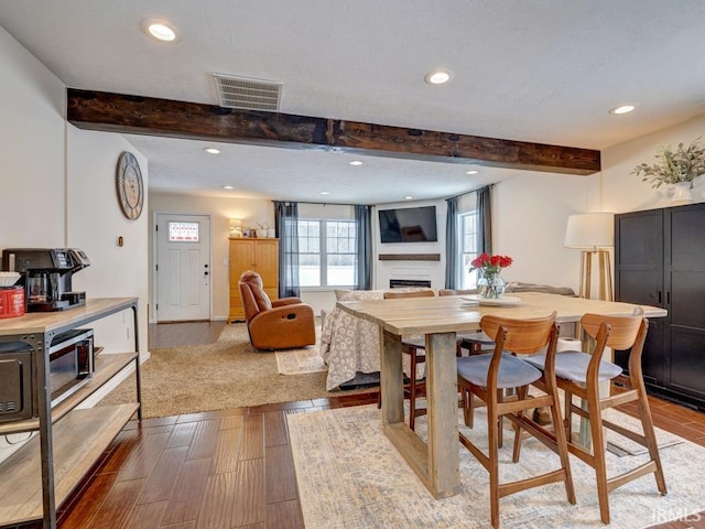 dining space with light wood-style flooring, recessed lighting, a fireplace, visible vents, and beam ceiling