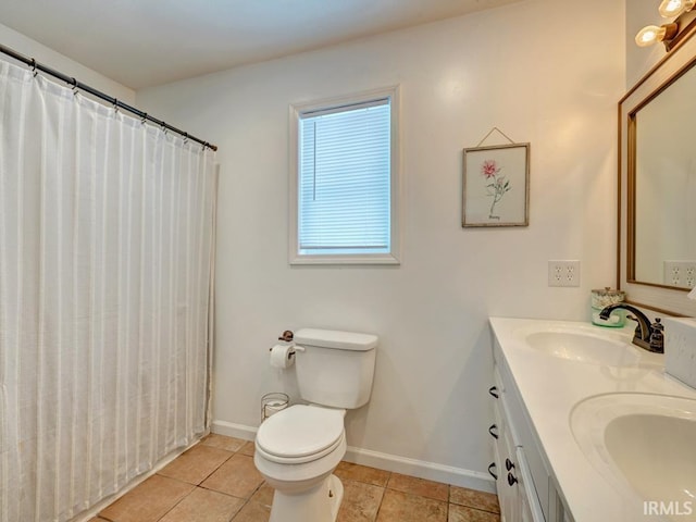 full bath featuring double vanity, a sink, and baseboards