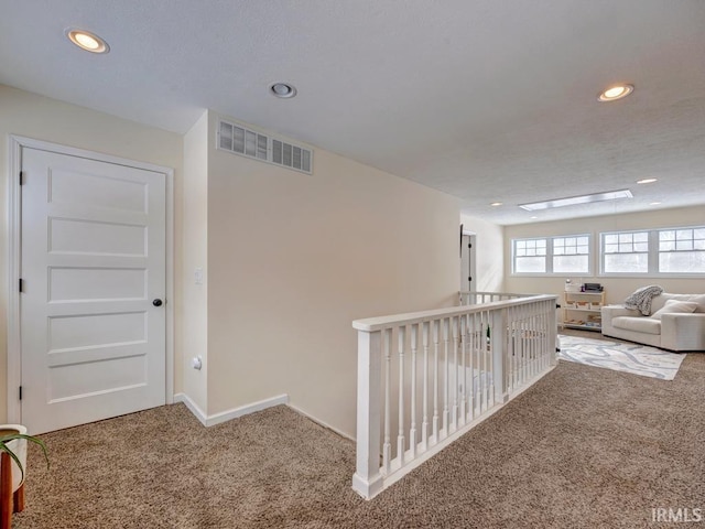 hall featuring baseboards, carpet, visible vents, and recessed lighting